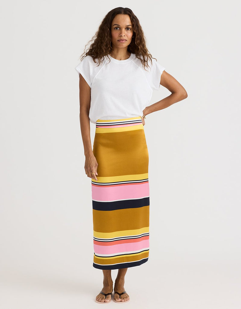 Woman wearing a white top and a long, multicolored striped skirt on a white background