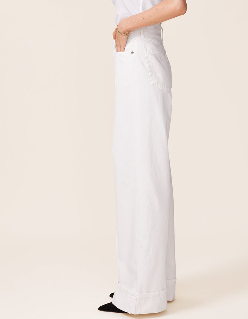 White wide leg jeans worn by a person on a beige background