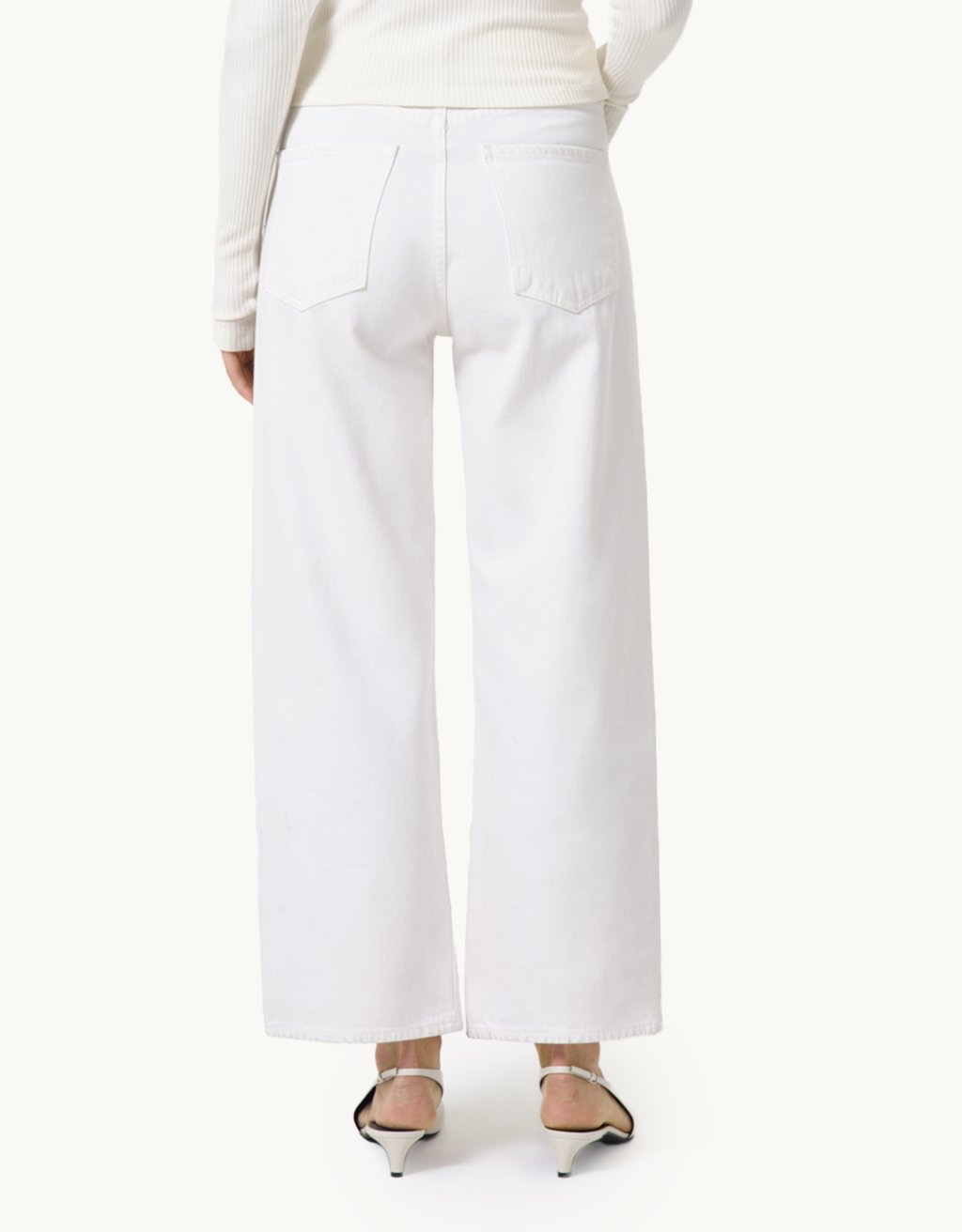 Ivory high-rise jeans and a cream top worn by a person on a neutral background