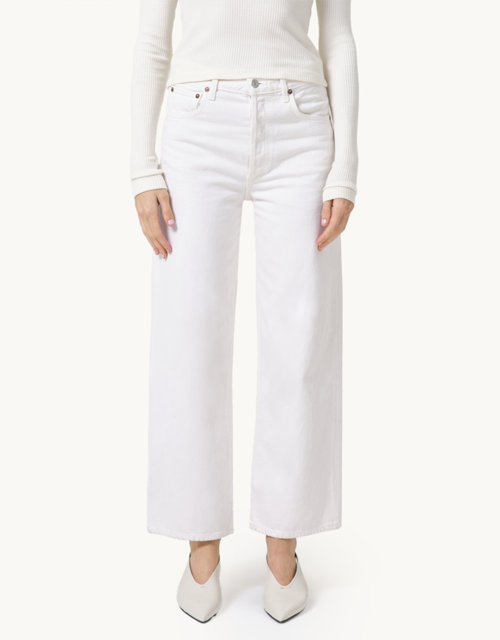 Person wearing high-rise ivory jeans and a cream top on a neutral background