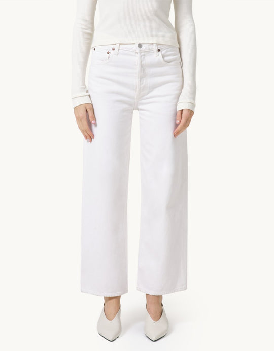 Person wearing high-rise ivory jeans and a cream top on a neutral background