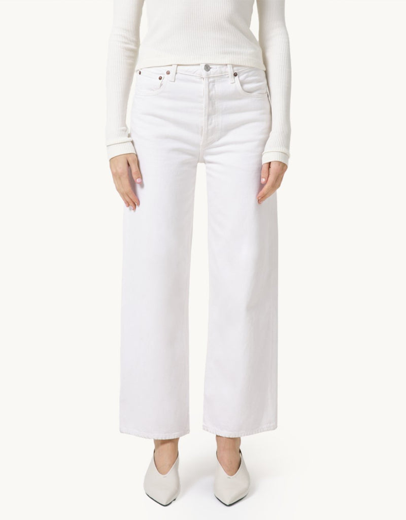Person wearing high-rise ivory jeans and a cream top on a neutral background