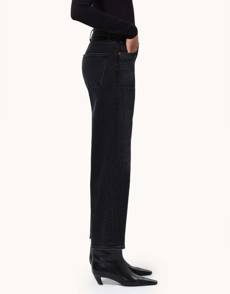 Person wearing black jeans with a black top and booties on a neutral background