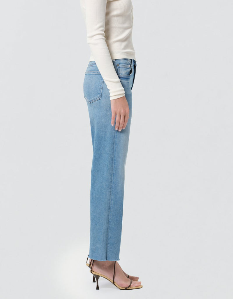 Person wearing light blue jeans and a white top on a plain background