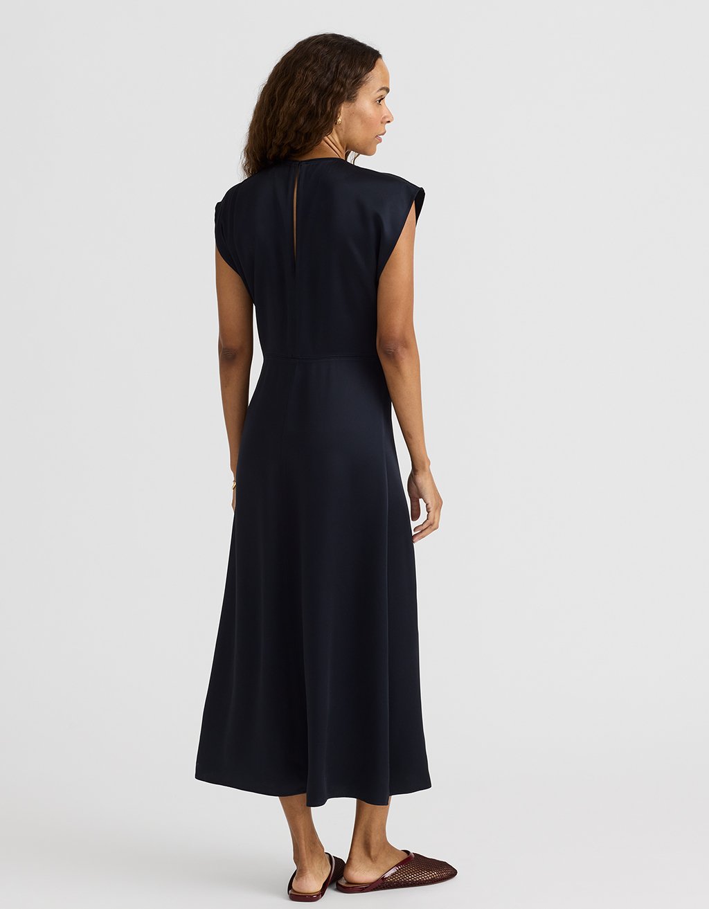 Woman wearing a navy satin midi length dress on a white background