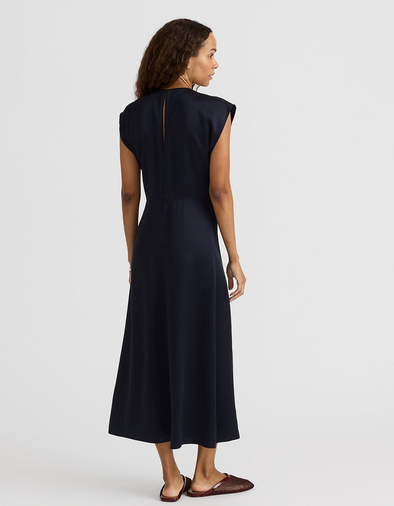 Woman wearing a navy satin midi length dress on a white background