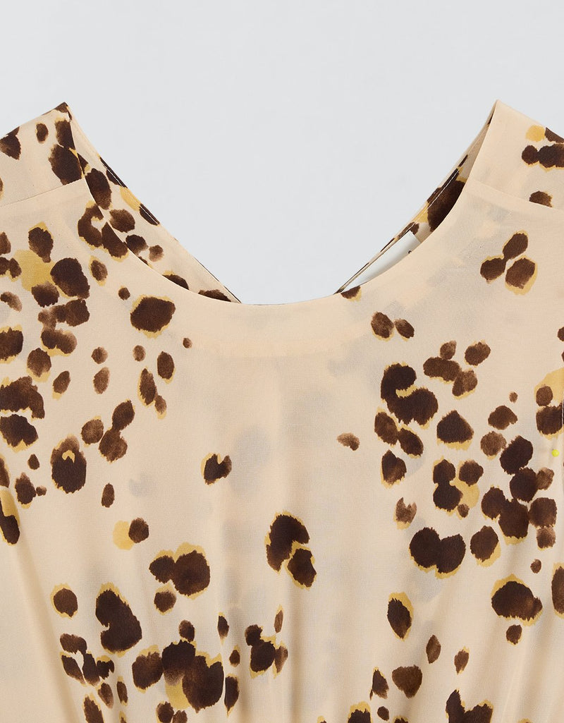 Close-up of a dress neckline with brown dot pattern on a light gray background