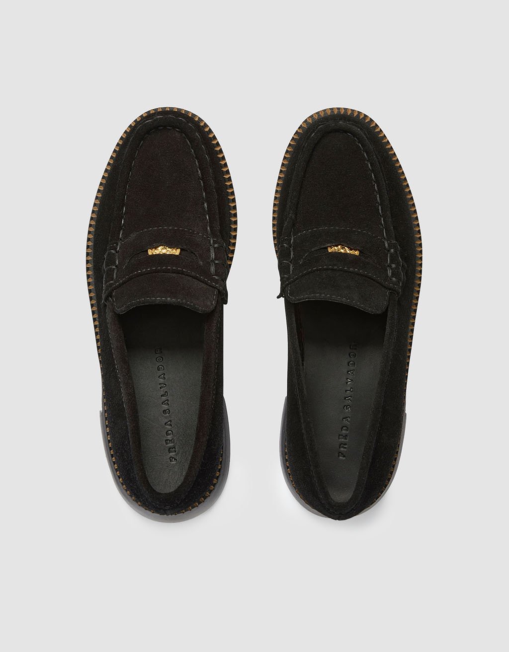 Top view of a pair of black suede loafers on a light gray background
