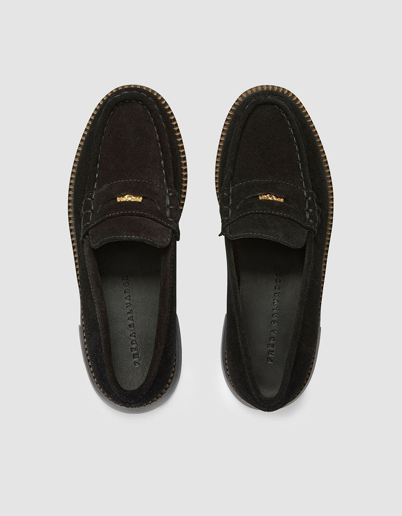 Top view of a pair of black suede loafers on a light gray background