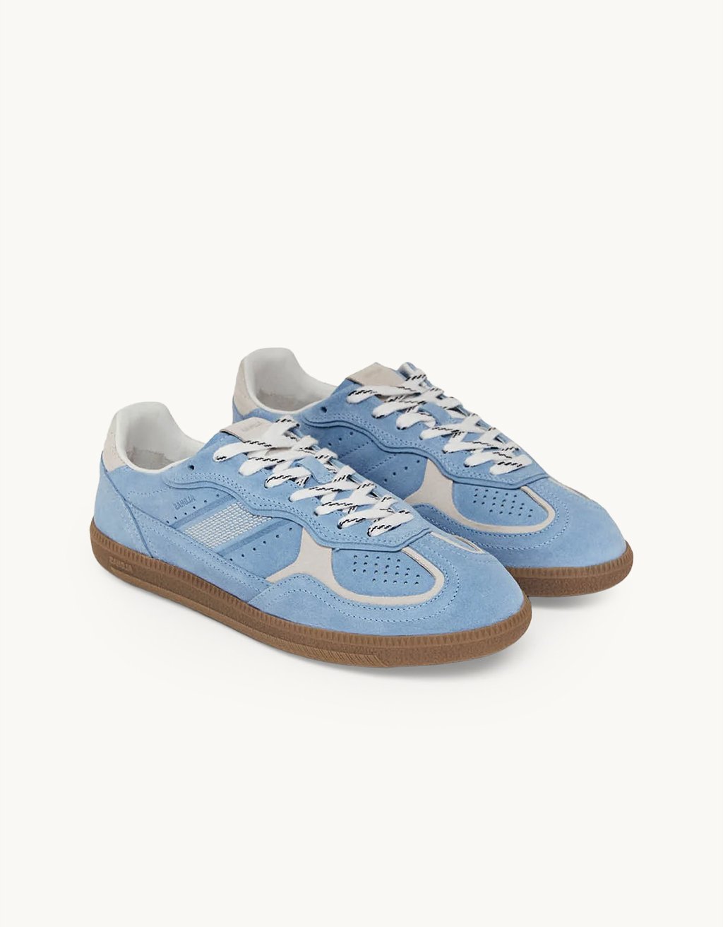Cornflower blue suede low top sneakers with white accent details and rubber soles on a light gray background