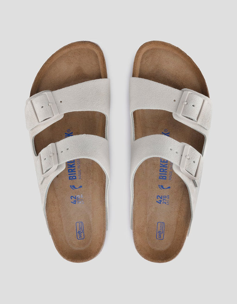Pair of white sandals with brown soles on a light gray background