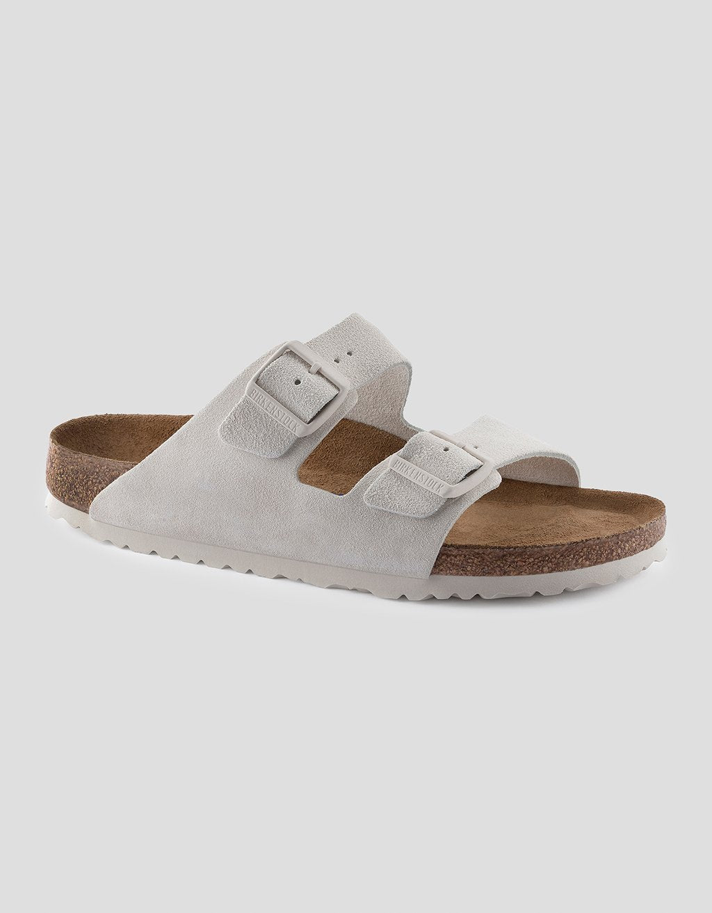 White sandal with brown sole on a light gray background