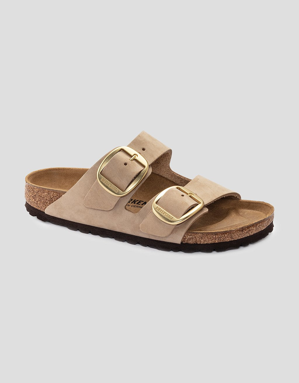 Beige Birkenstock sandal with gold buckles on a light gray background