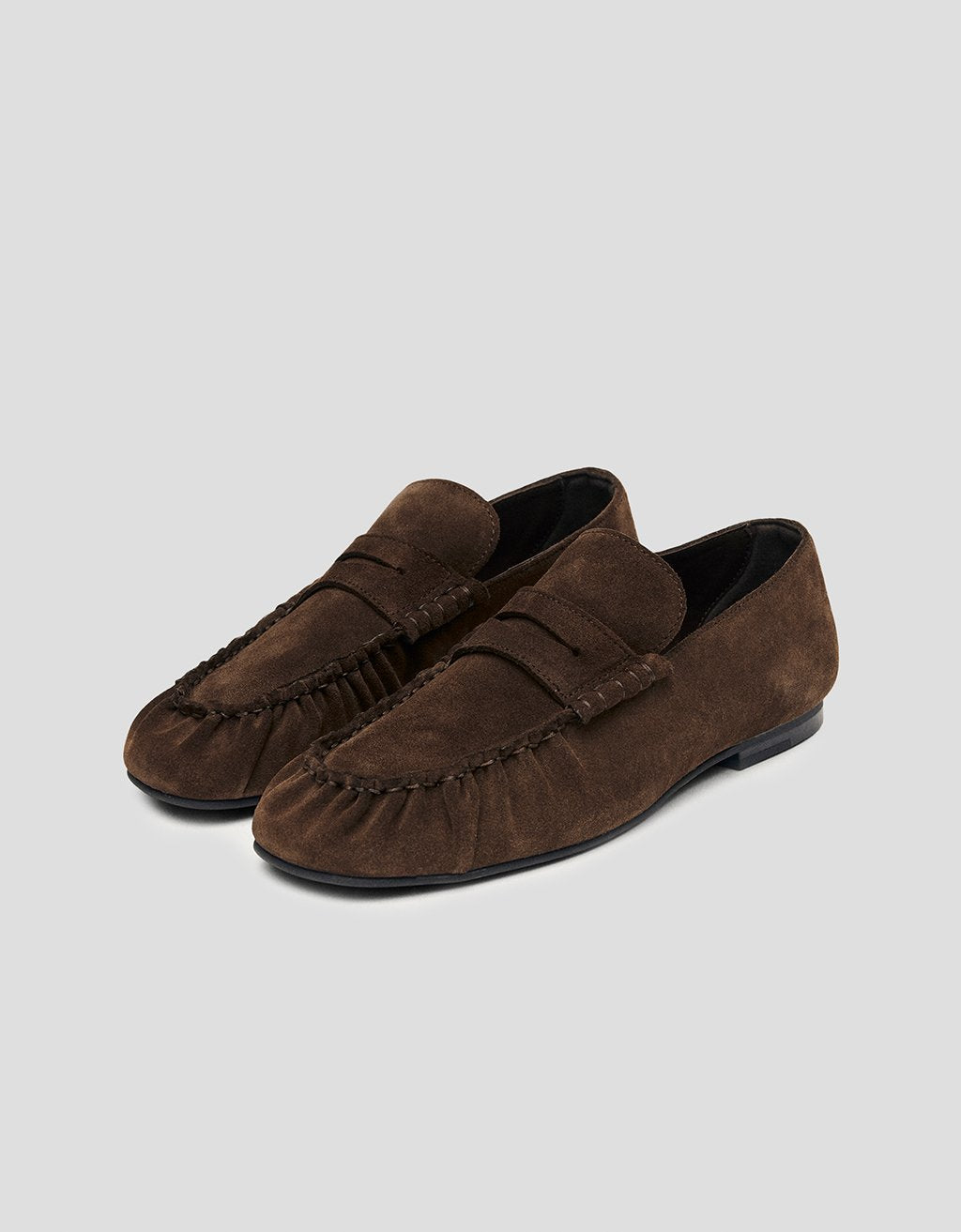 Pair of brown suede loafers on a light gray background