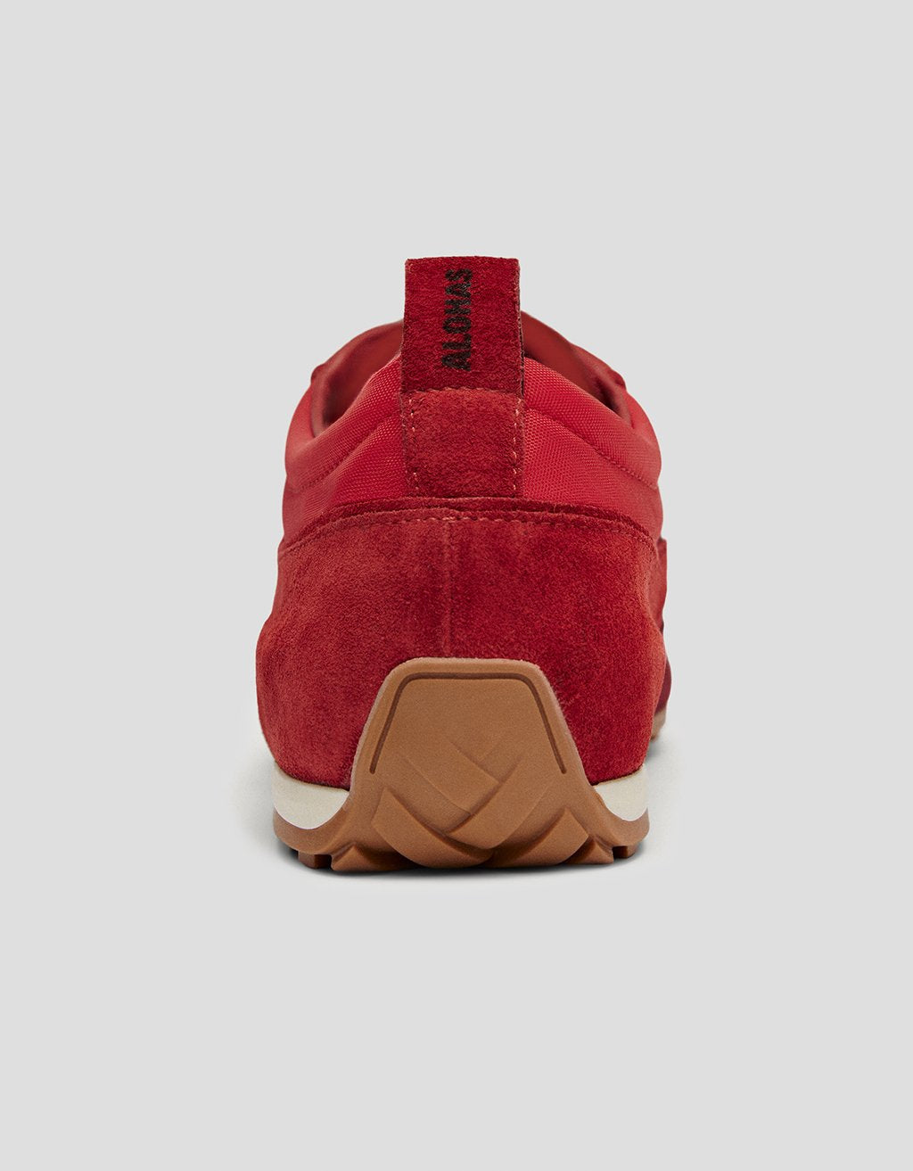Back view of a red leather sneaker with a brown rubber sole on a light gray background