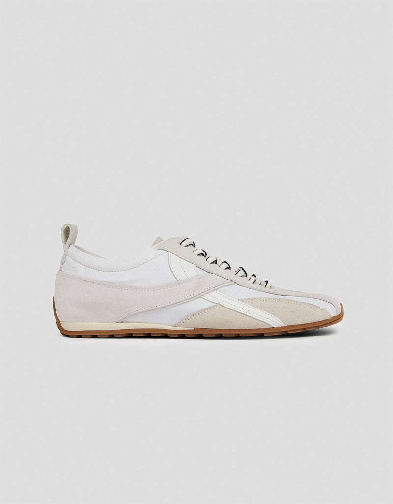 Profile view of a white leather sneaker with a brown rubber sole on a light gray background