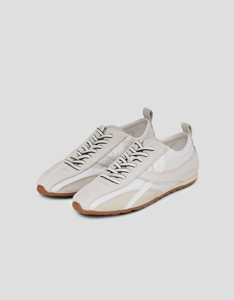 Pair of white leather sneakers with rubber soles on a light gray background