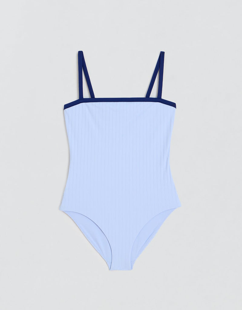 Ribbed light blue swimsuit with navy thin straps on a light gray background