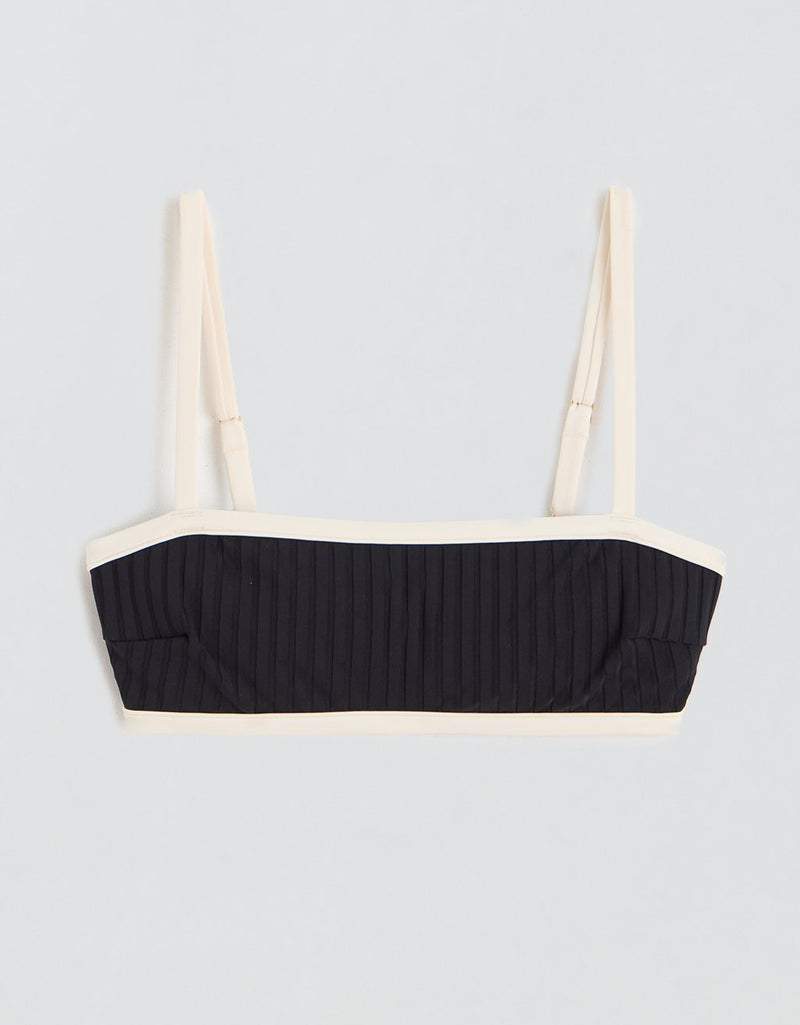 Black ribbed bikini top with contrast ivory straps and trim on a light gray background