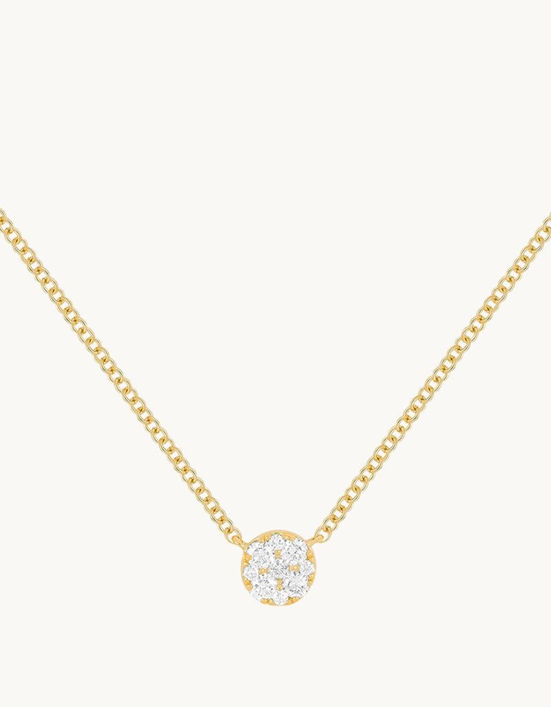 Close-up of a round diamond pendant on a 14k yellow gold chain against a light gray background