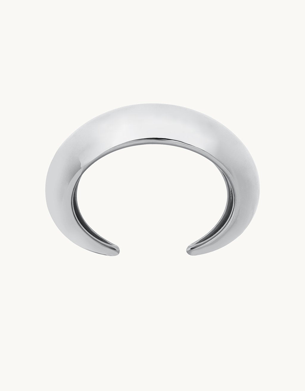 Silver crescent-shaped cuff bracelet on a plain background