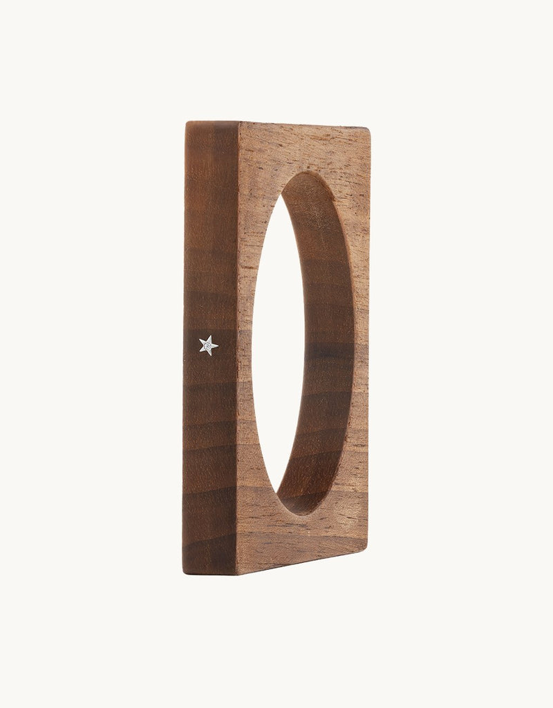 Square wooden bracelet with a star detail on a light gray background