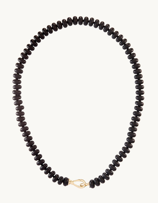 Black onyx rondelle beads strung on a knotted silk cord on a light gray background