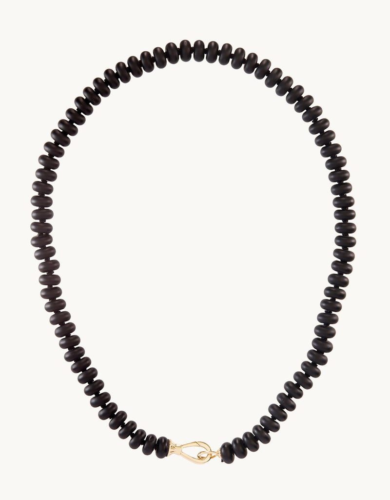 Black onyx rondelle beads strung on a knotted silk cord on a light gray background