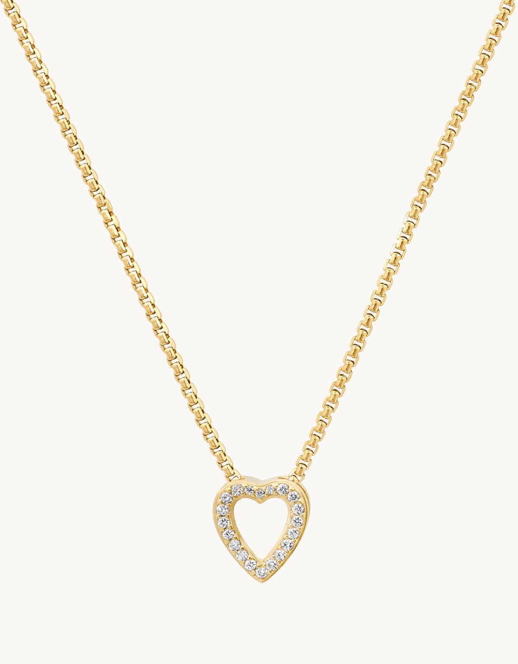 Gold heart-shaped pendant with diamond accents on a gold chain against a plain background