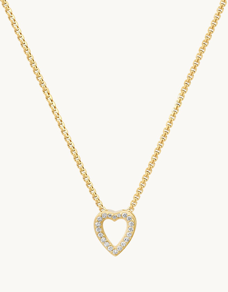 Gold heart-shaped pendant with diamond accents on a gold chain against a plain background