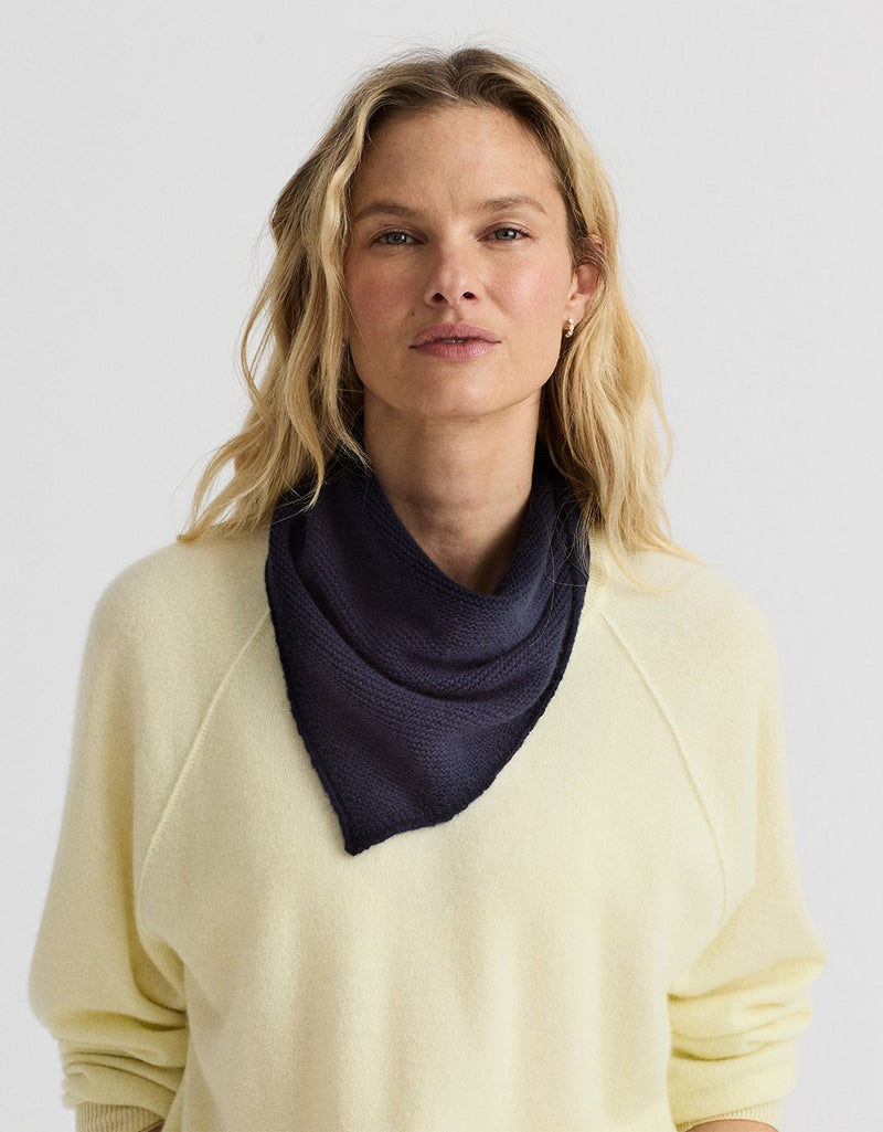 Woman wearing a navy blue cashmere scarf around her neck against a plain background