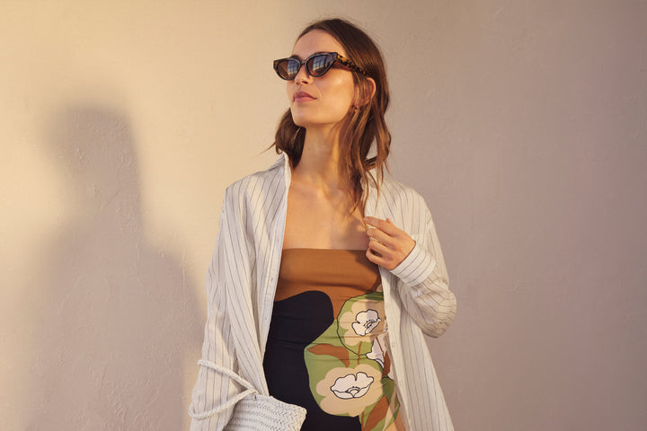 Model wearing sunglasses and printed swimsuit.